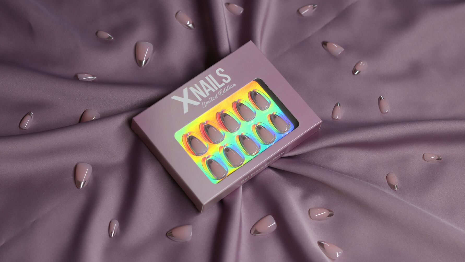 Limited Edition XNails press-on nagels, lichtroze amandelvormig met chrome-toppen, in en buiten de verpakking op paarse stof