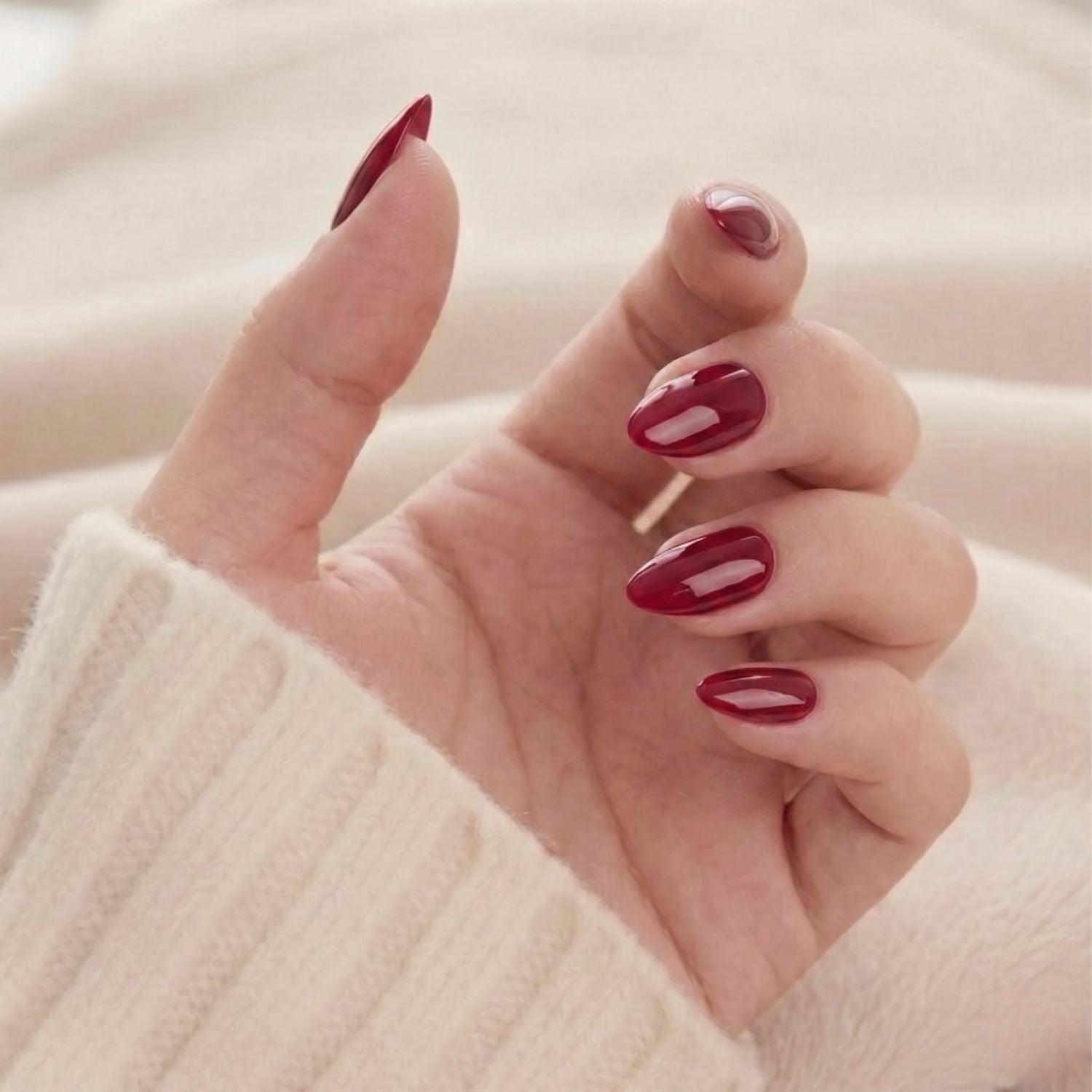 Ruby Romance: glanzende wijnrode amandelvormige press-on nagels, elegante nepnagel-manicure op hand in zachte trui