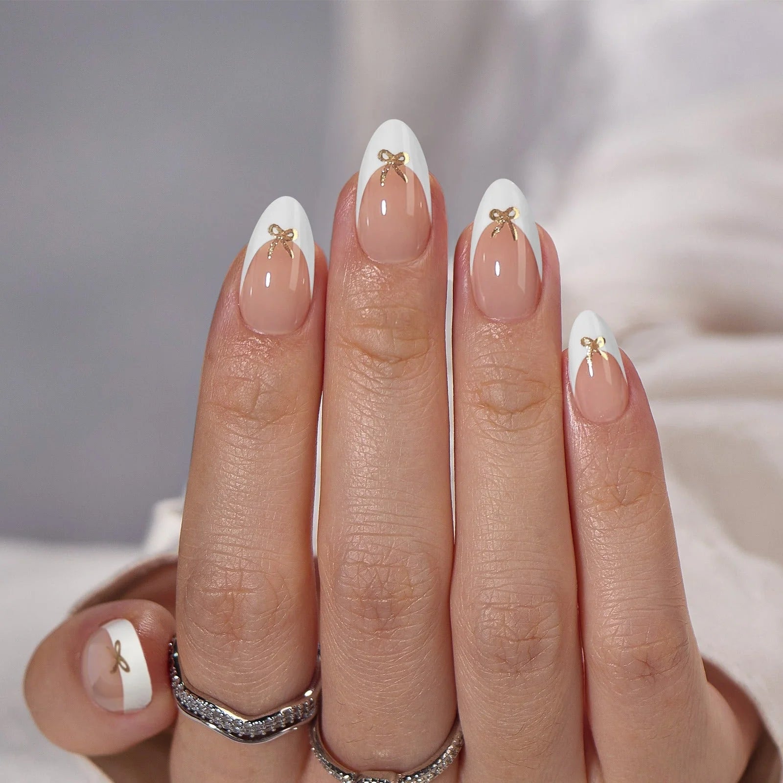 Blushing Bow press-on nagels macro – amandel franse tip met 3D gouden strik op witte stof