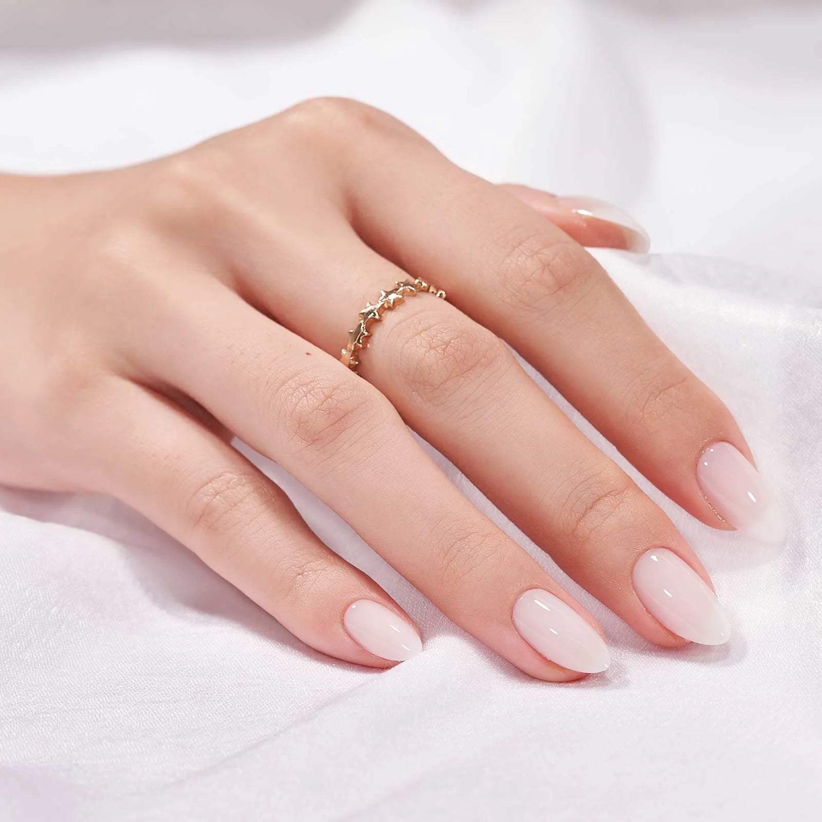 Satin Snow press-on nagels styling – nude amandelnagels met gouden ring tegen witte satijn
