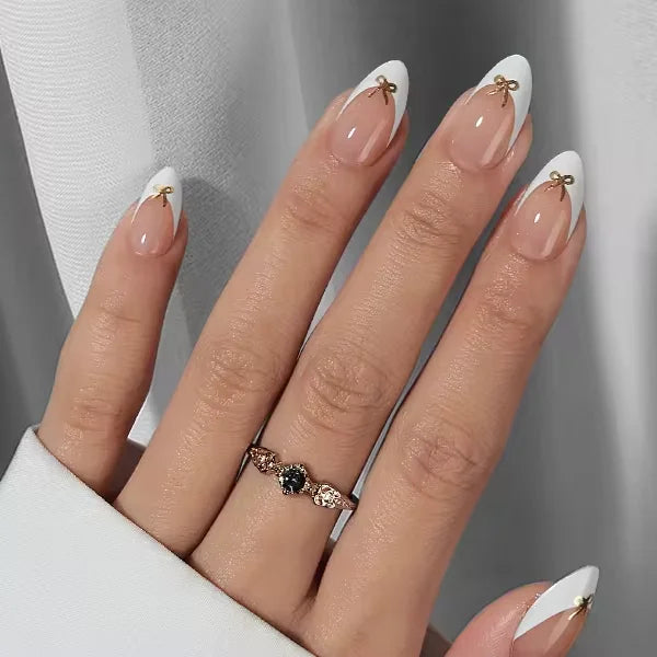 Blushing Bow amandelvormige gelnagels – franse witte tip met gouden strik-detail en zilveren ring met hartsteen