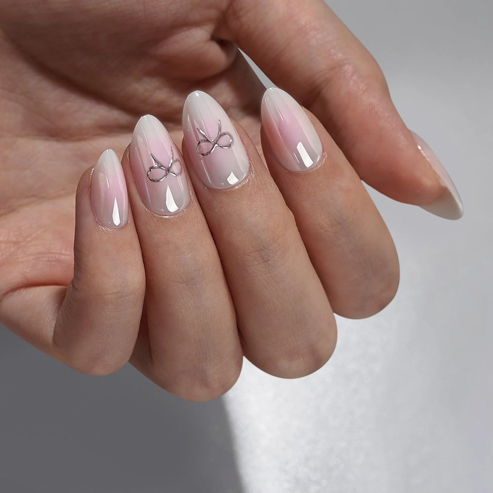 Aura Amoré amandelvormige press-on nagels – zachtroze aura met zilveren strik-accentnagels