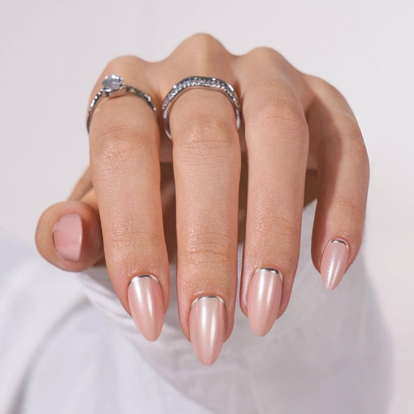 Shimmering Silver press-on nagels close-up – amandelvorm met zilveren rand en kristallen ringen tegen witte doek