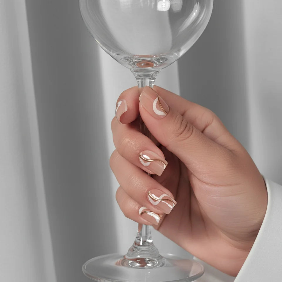 Summer Swirl press-on nagels styling – hand houdt wijnglas vast, korte vierkante nagels met gouden swirl