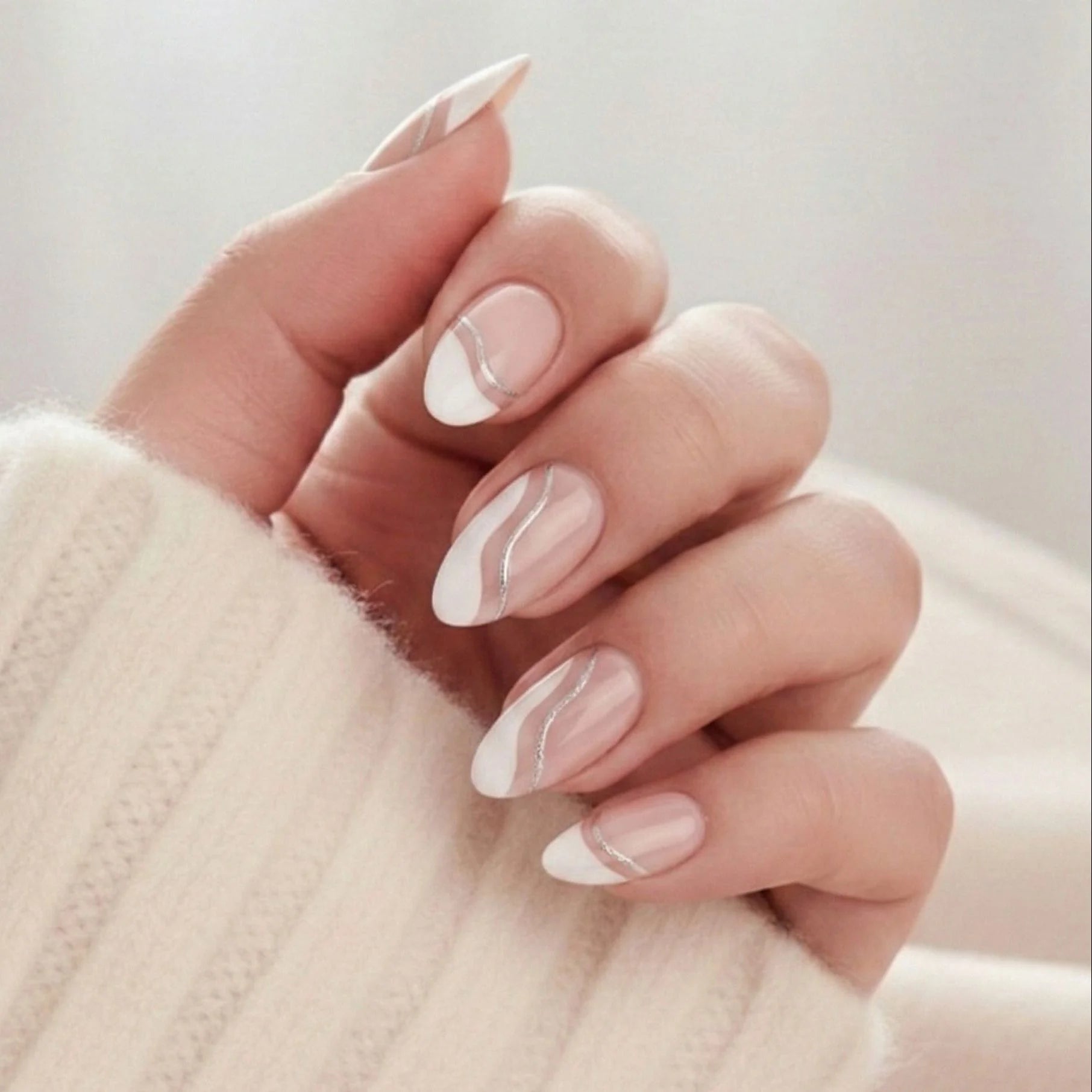 Metallic Merge press-on nails – amandelvormige kunstnagels met witte Franse tip en zilveren swirl tegen beige trui