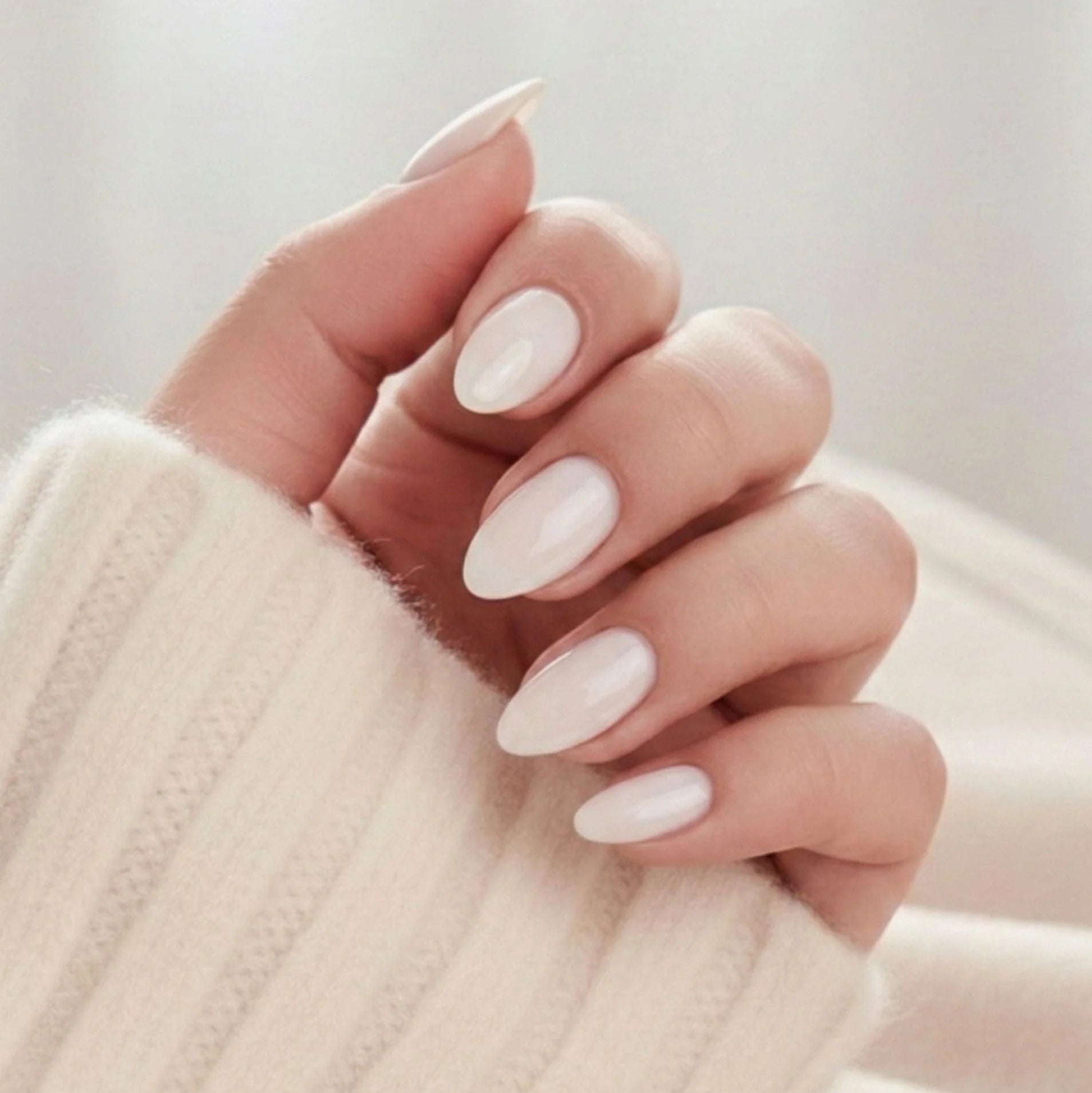 Satin Snow press-on nagels – crèmewitte amandelmanicure met zachte glans tegen lichte gebreide trui