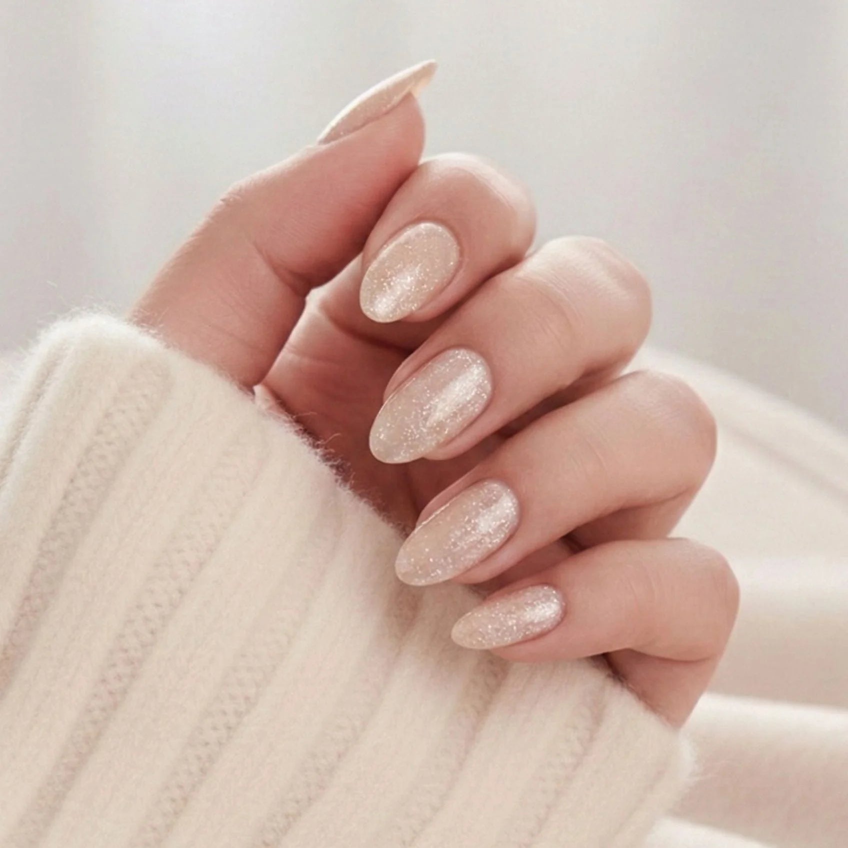 Candy Chrome press-on nagels – champagne glitter shimmer in amandelvorm tegen crème gebreide trui