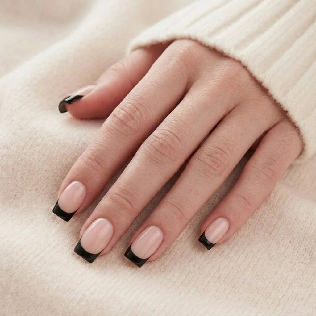 Sleek Silhouette nagels op hand – nude vierkante gelnagels met zwarte Franse tip rusten tegen beige trui