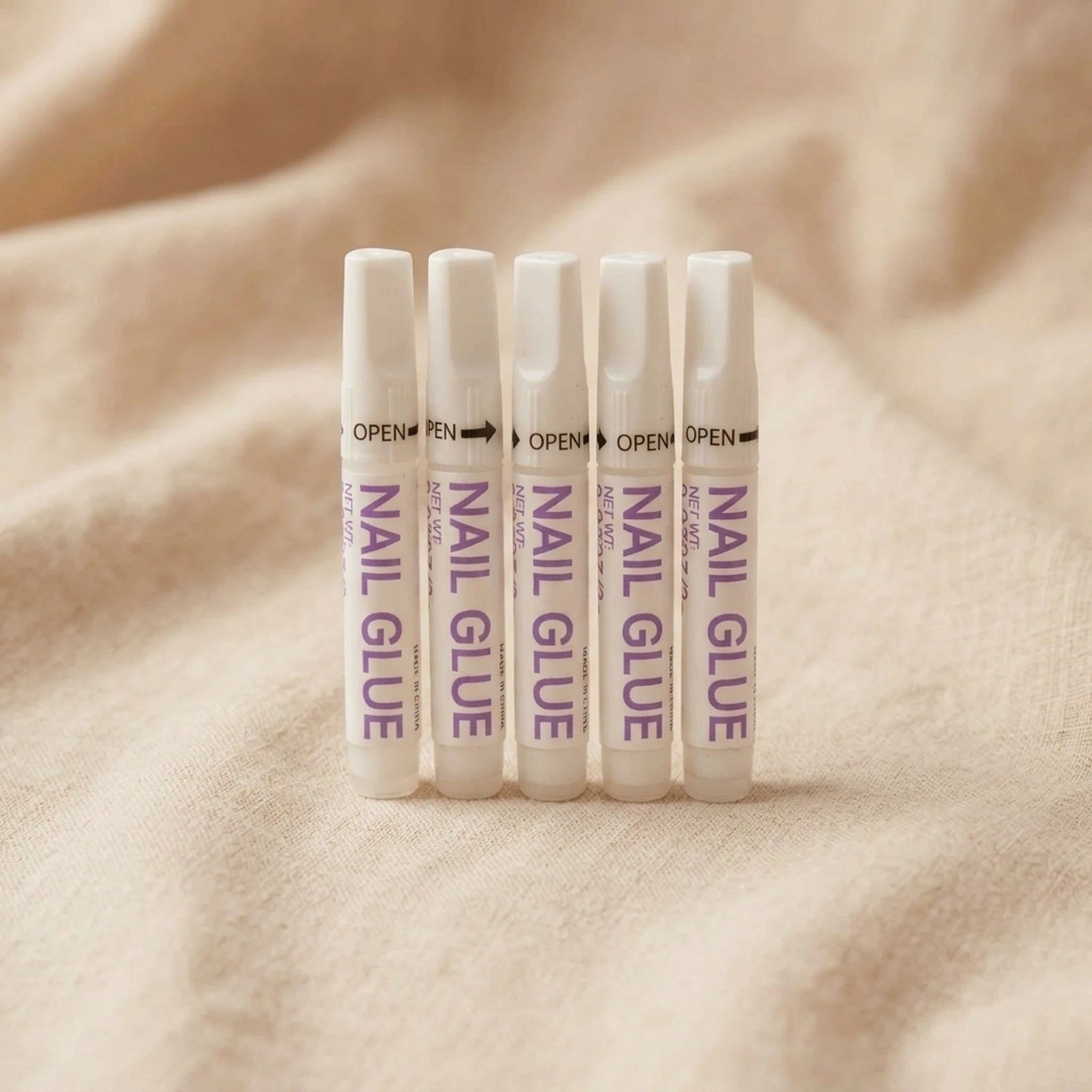 XNails Nail Glue nagellim på beige bakgrund
