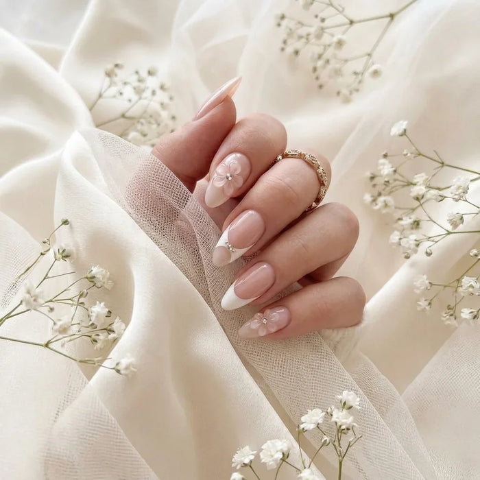 Hand van de bruid met Bridal Bloom press-on nagels op ivoren zijde