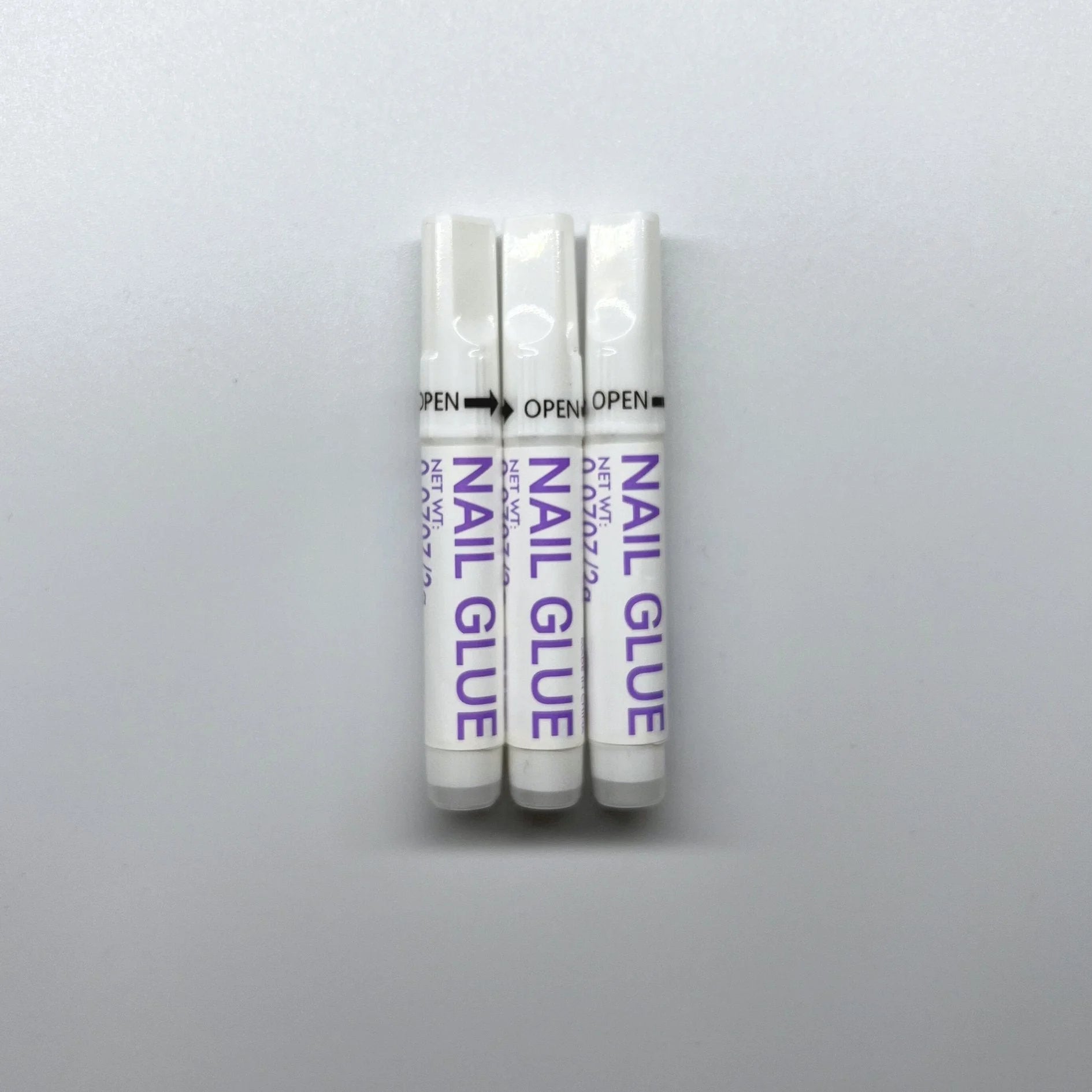 XGlue nagellijm 3-pack – drie witte tubes Nail Glue voor press-on nagels tegen witte achtergrond