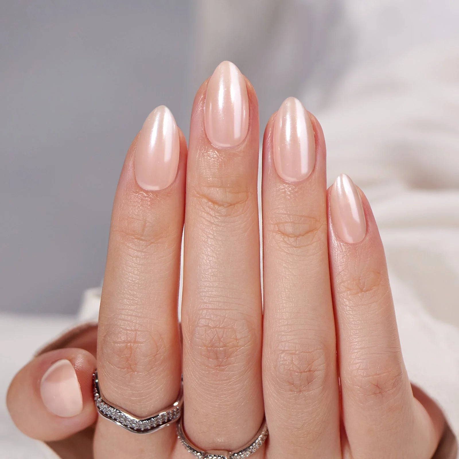 Heavenly Halo gelnagels close-up – pearl shimmer in amandelvorm tegen witte satijn
