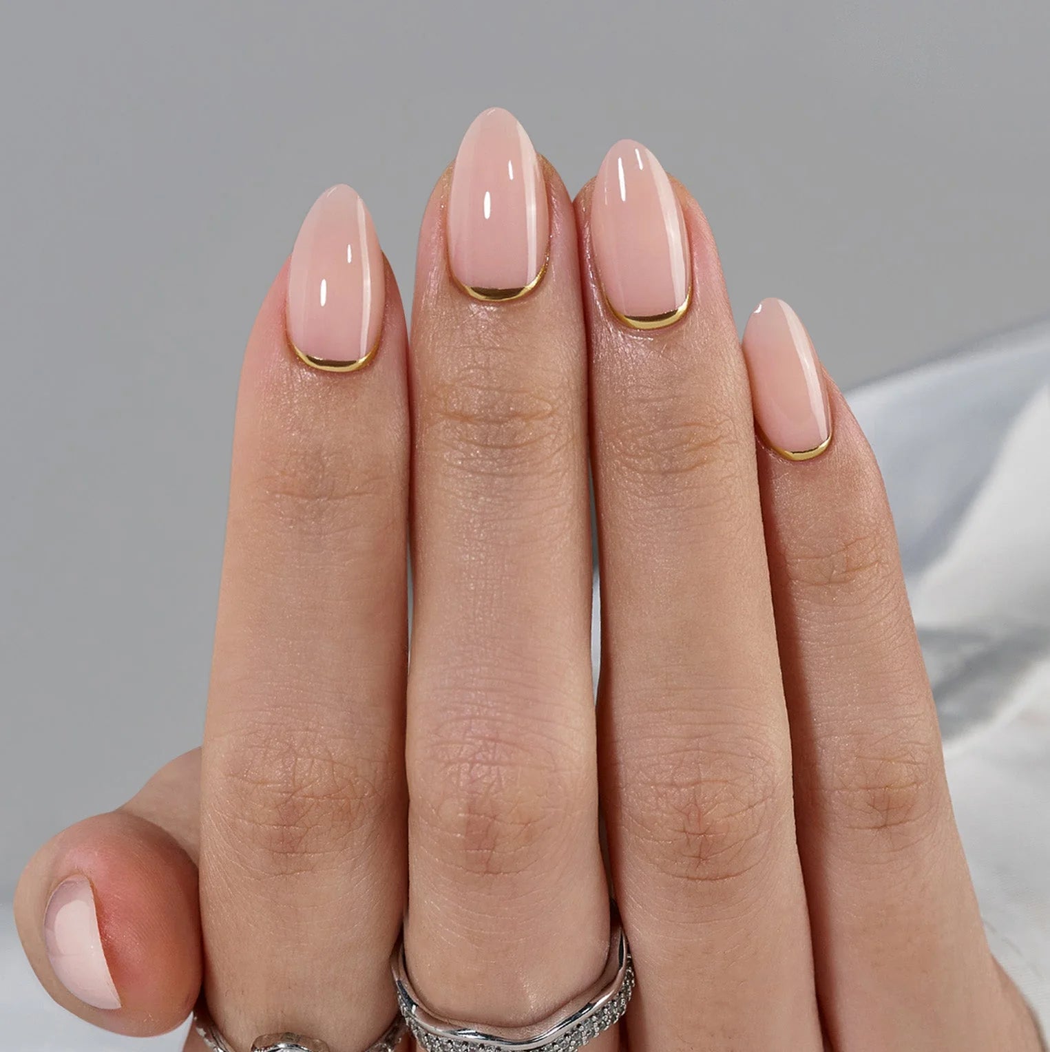 Golden Glimmer press-on nagels close-up – nude basis en gouden lijn langs de nagelriem