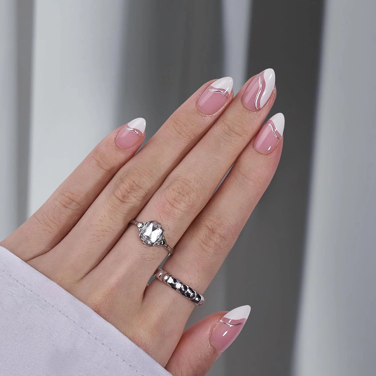 Metallic Merge press-on nails op de hand – amandelvormige kunstnagels met zilveren swirl en zilveren ring met kristal