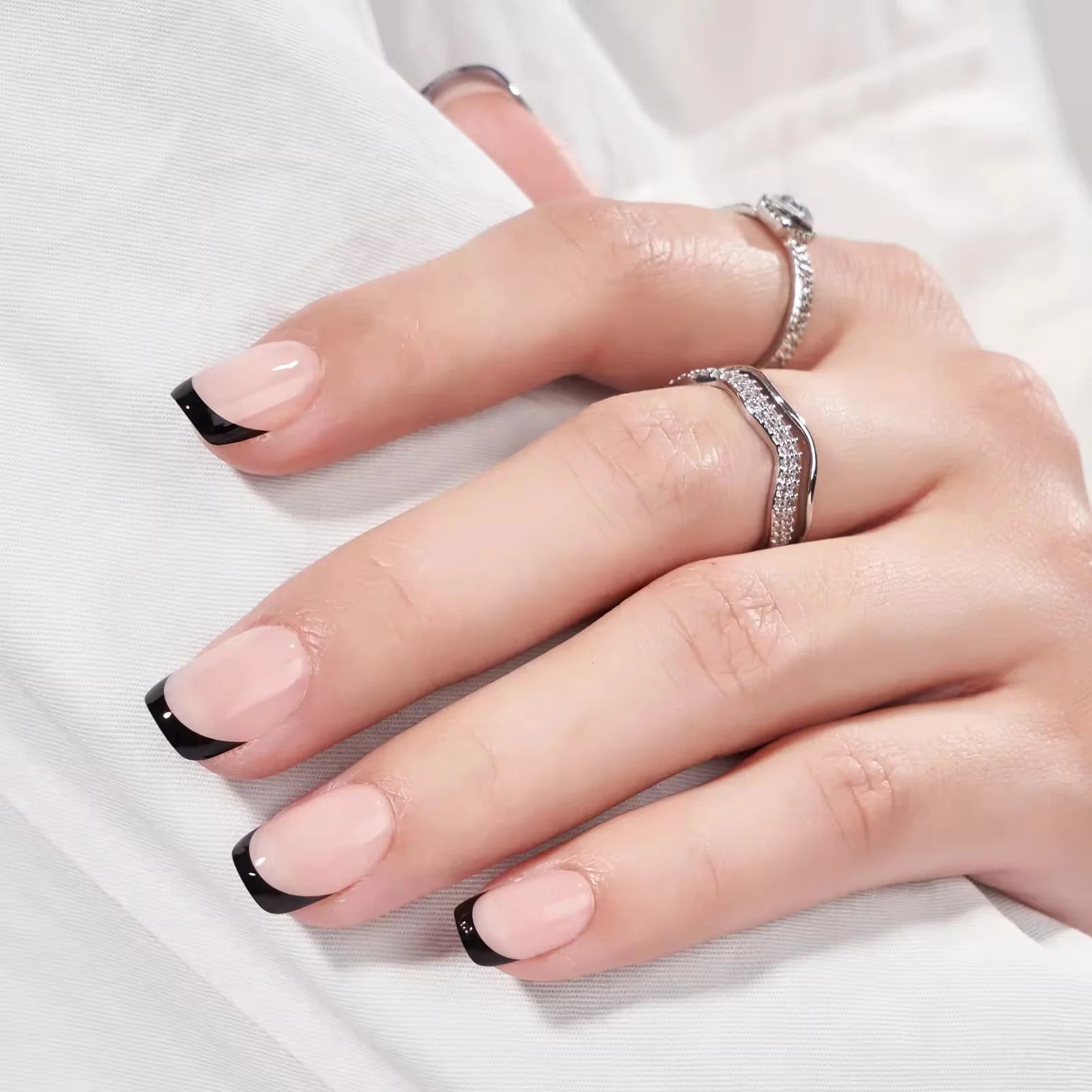 Sleek Silhouette press-on nagels styling – nude vierkante gelnagels met zwarte tip tegen witte doek