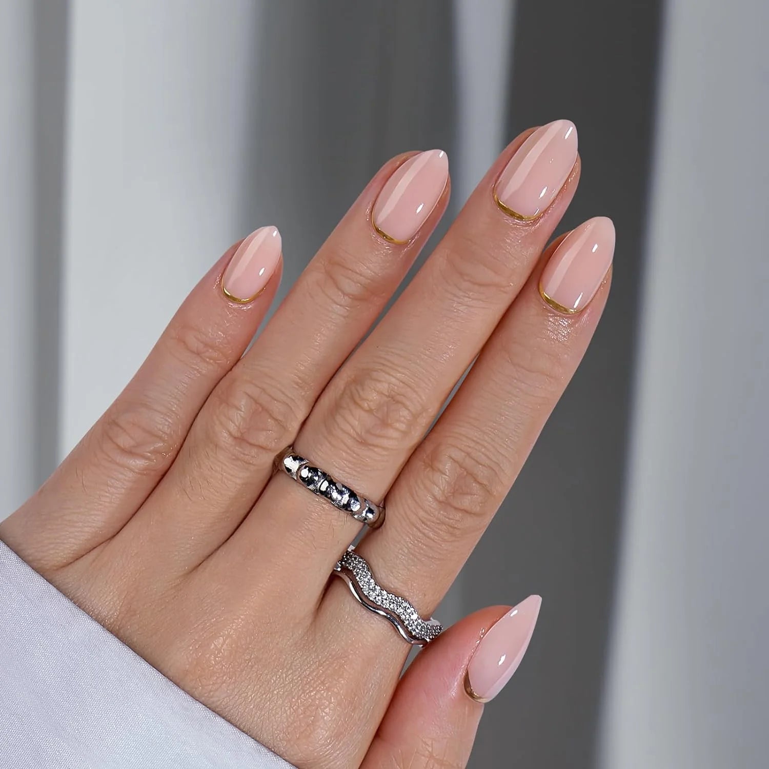 Golden Glimmer amandelvormige plaknagels – peach nude met gouden swirl en zilveren ringen