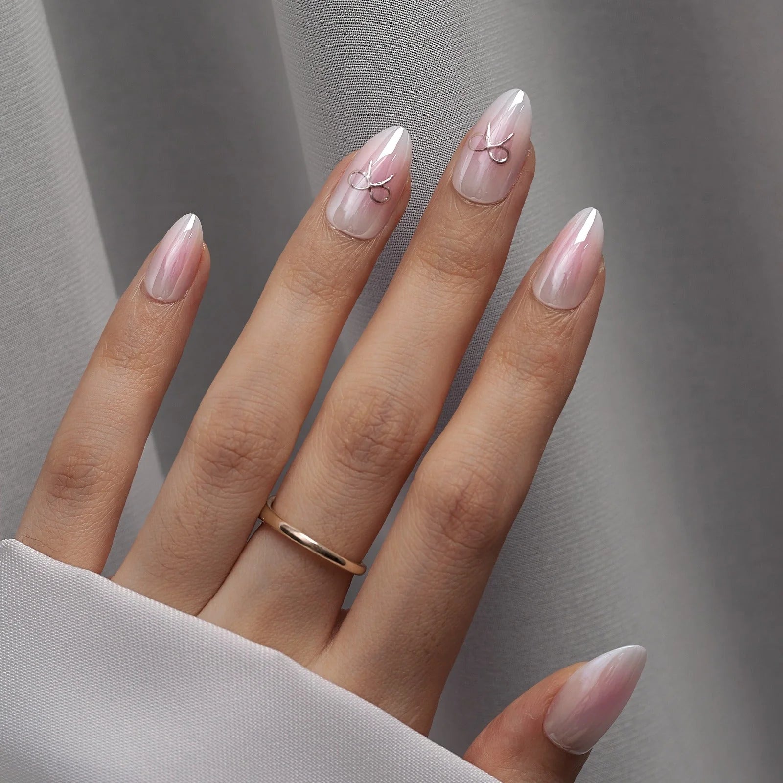 Aura Amoré press-on nagels close-up – roze parelwitte aura in amandelvorm tegen grijze satijn