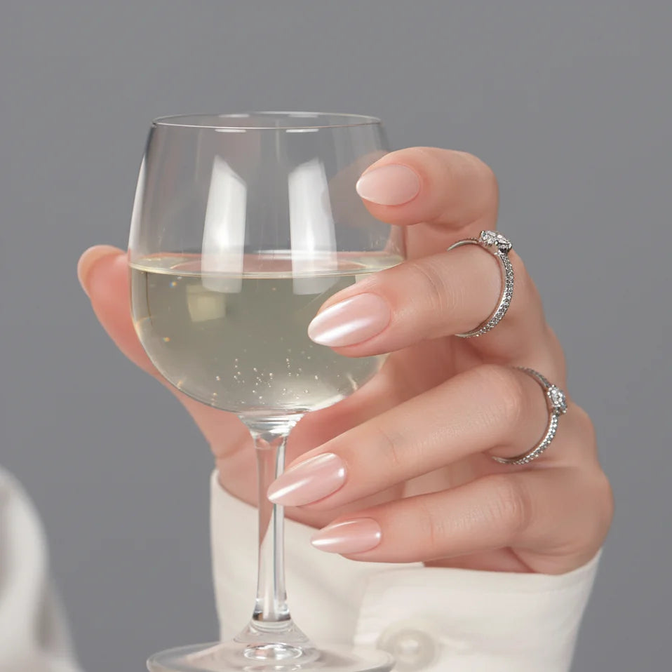 Heavenly Halo press-on nagels styling – nude pearl glow met wijnglas en zilveren ringen