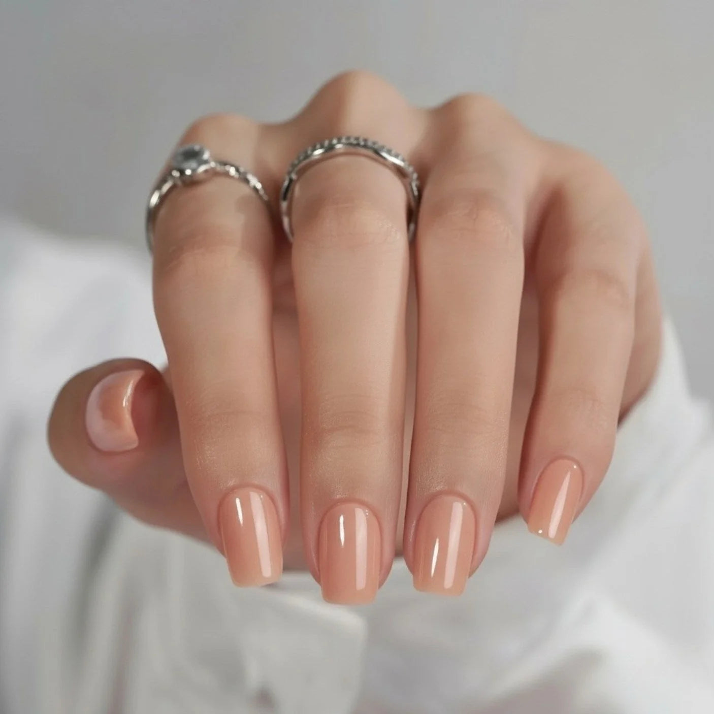 Honey Heaven kunstnagels close-up – korte vierkante gelnagels in peach-nude met zilveren ringen