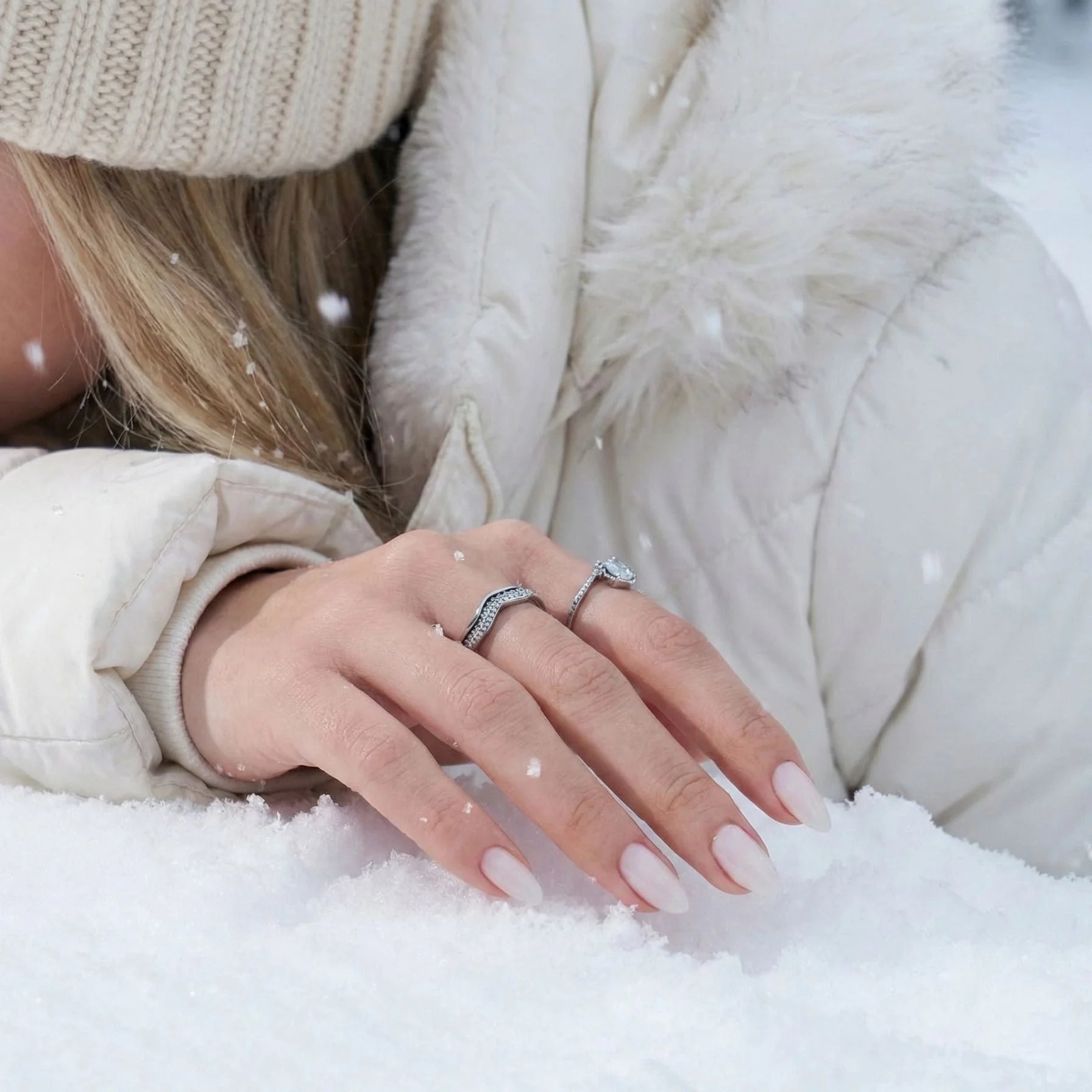 Satin Snow plaknagels lifestyle – crèmewitte amandelnagels in sneeuwlandschap met donsjas