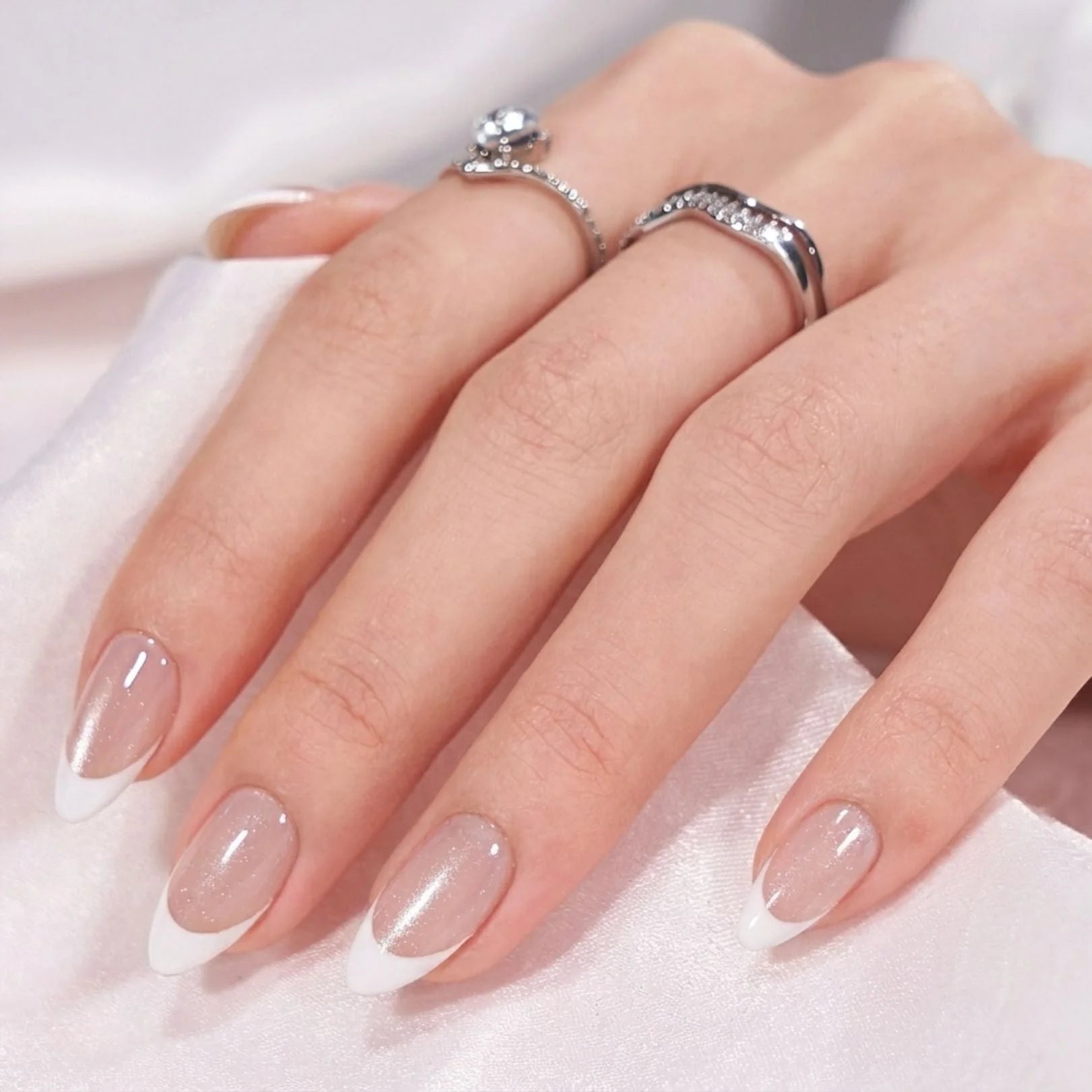 Sweet Sprinkle press-on nagels close-up – amandel Franse witte tip met zilveren ringen op wit satijn