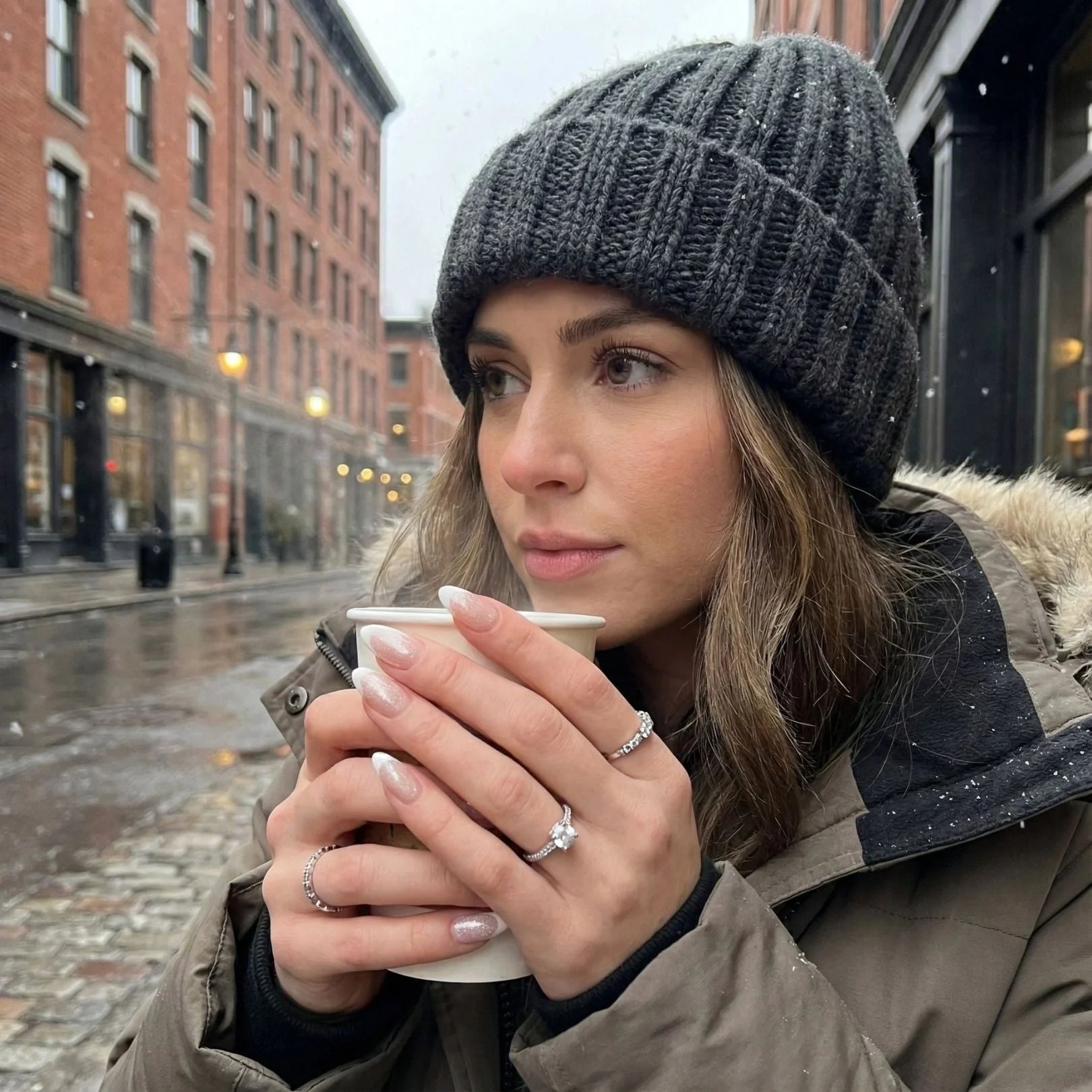 Sweet Sprinkle nagels lifestyle – amandelvormige nepnagels houden koffiekopje vast, grijze muts op besneeuwde straat