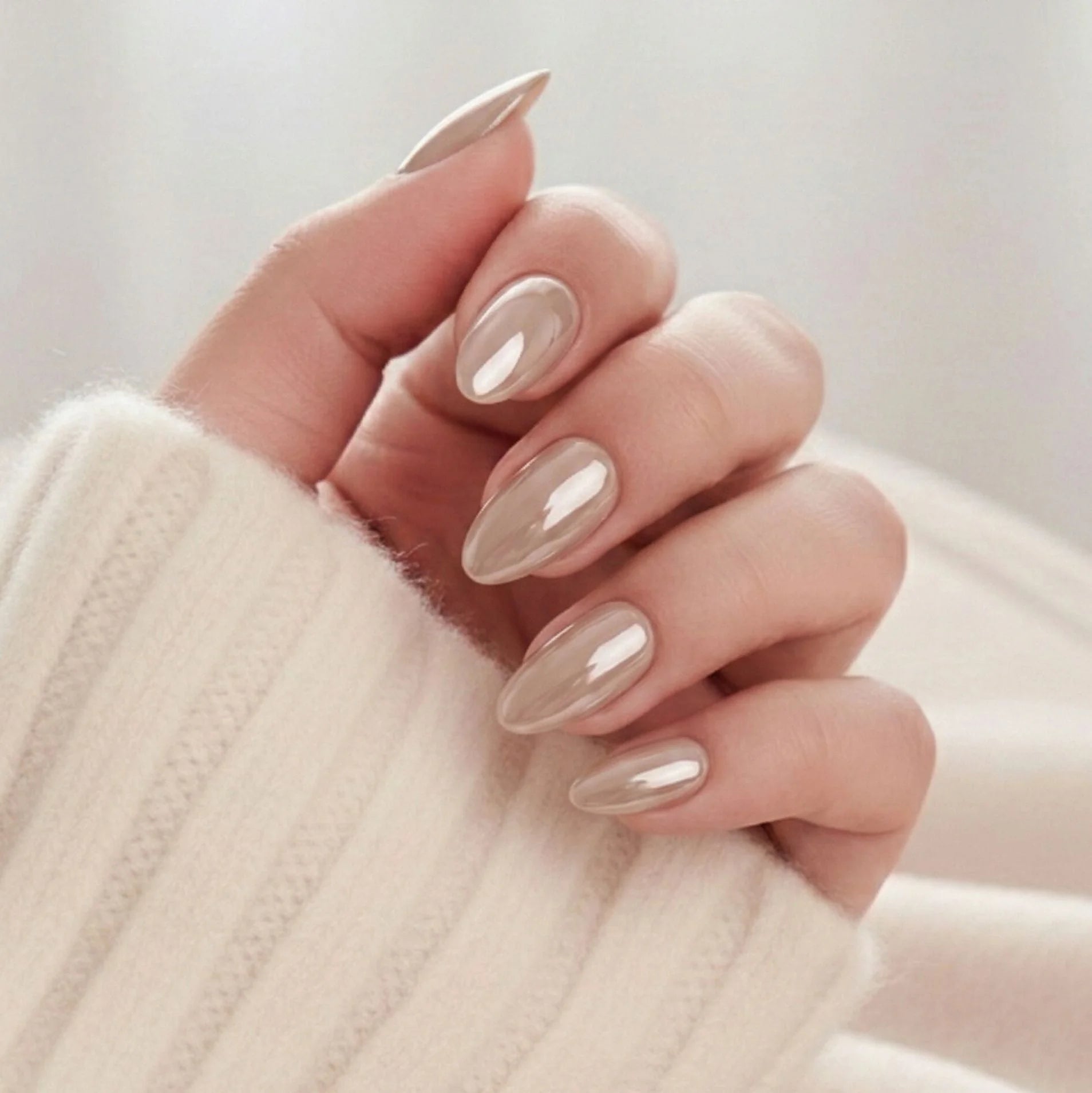 Pearly Perfection press-on nails – amandelvorm in pearl taupe met metallic glans tegen crèmewitte gebreide trui