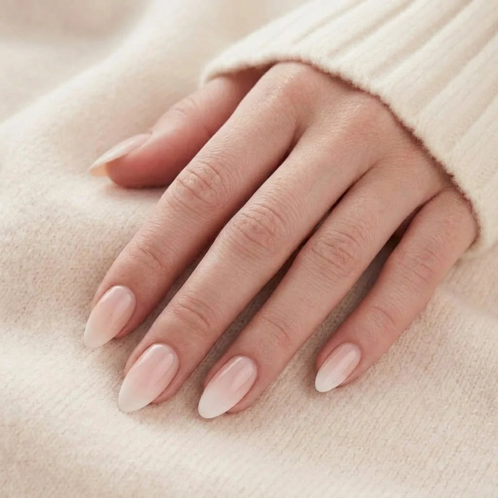 Dreamy Dip nagels op hand – nude roze ombre amandelnagels tegen beige gebreide trui
