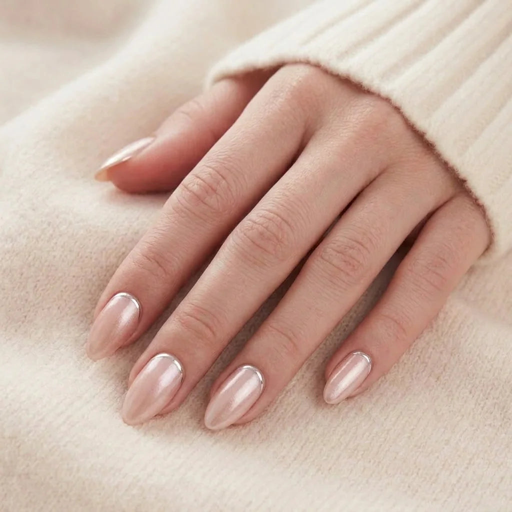 Shimmering Silver nagels op hand – amandelvormige gelnagels met parelglans rusten tegen crèmewitte trui