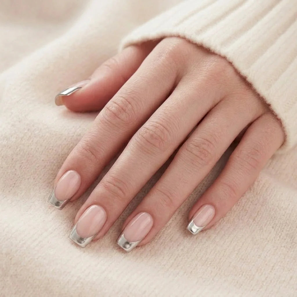 Fancy French plaknagels close-up – korte vierkante gelnagels met zilveren tip tegen beige gebreide trui