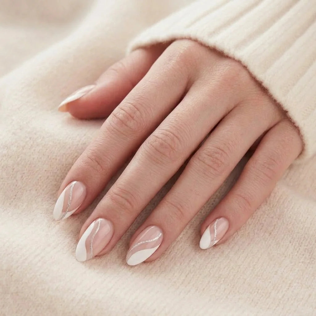 Metallic Merge kunstnagels close-up – amandelvormige gelnagels met zilveren swirl tegen zachte beige gebreide achtergrond