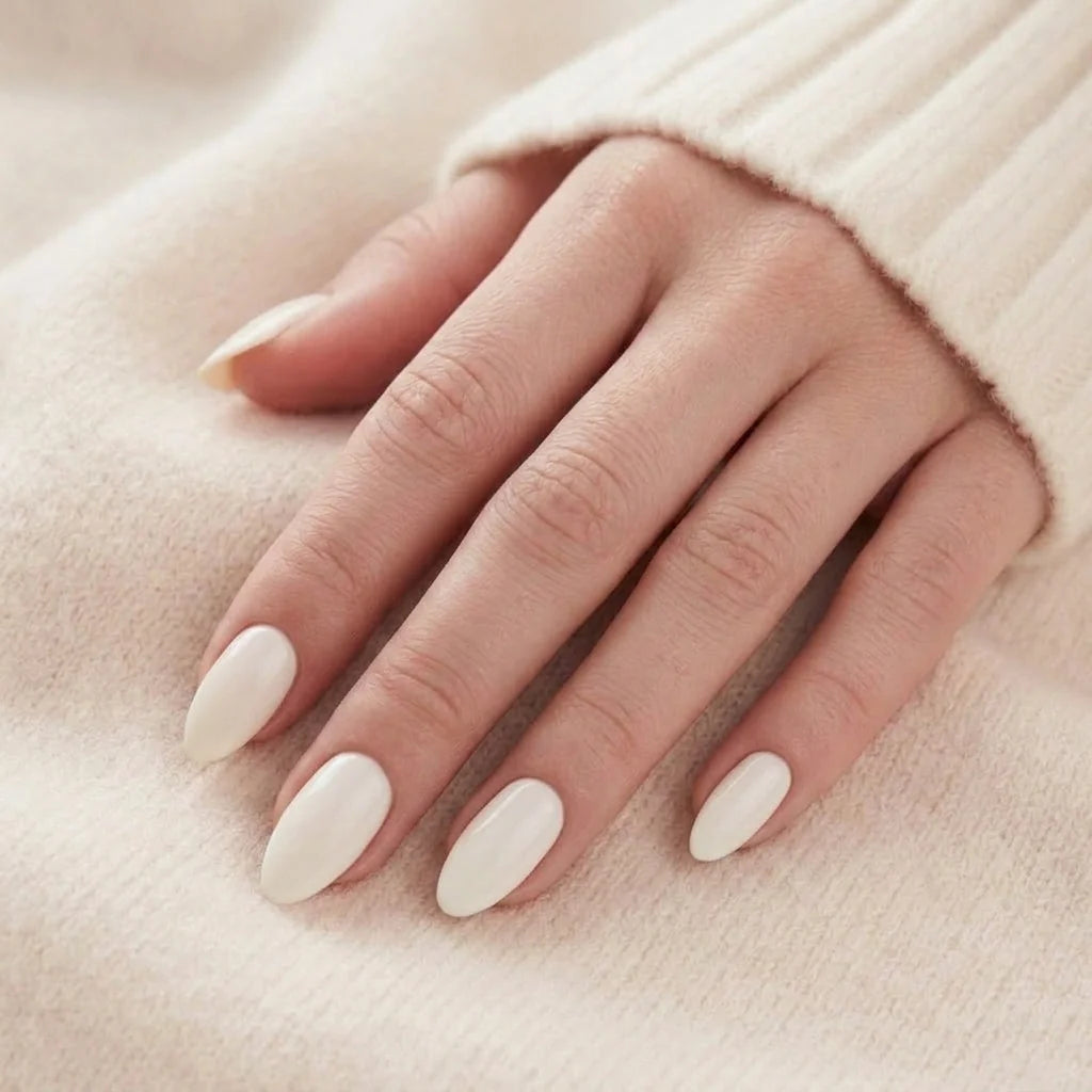Satin Snow plaknagels close-up – crèmewitte amandelnagels tegen beige kasjmier trui