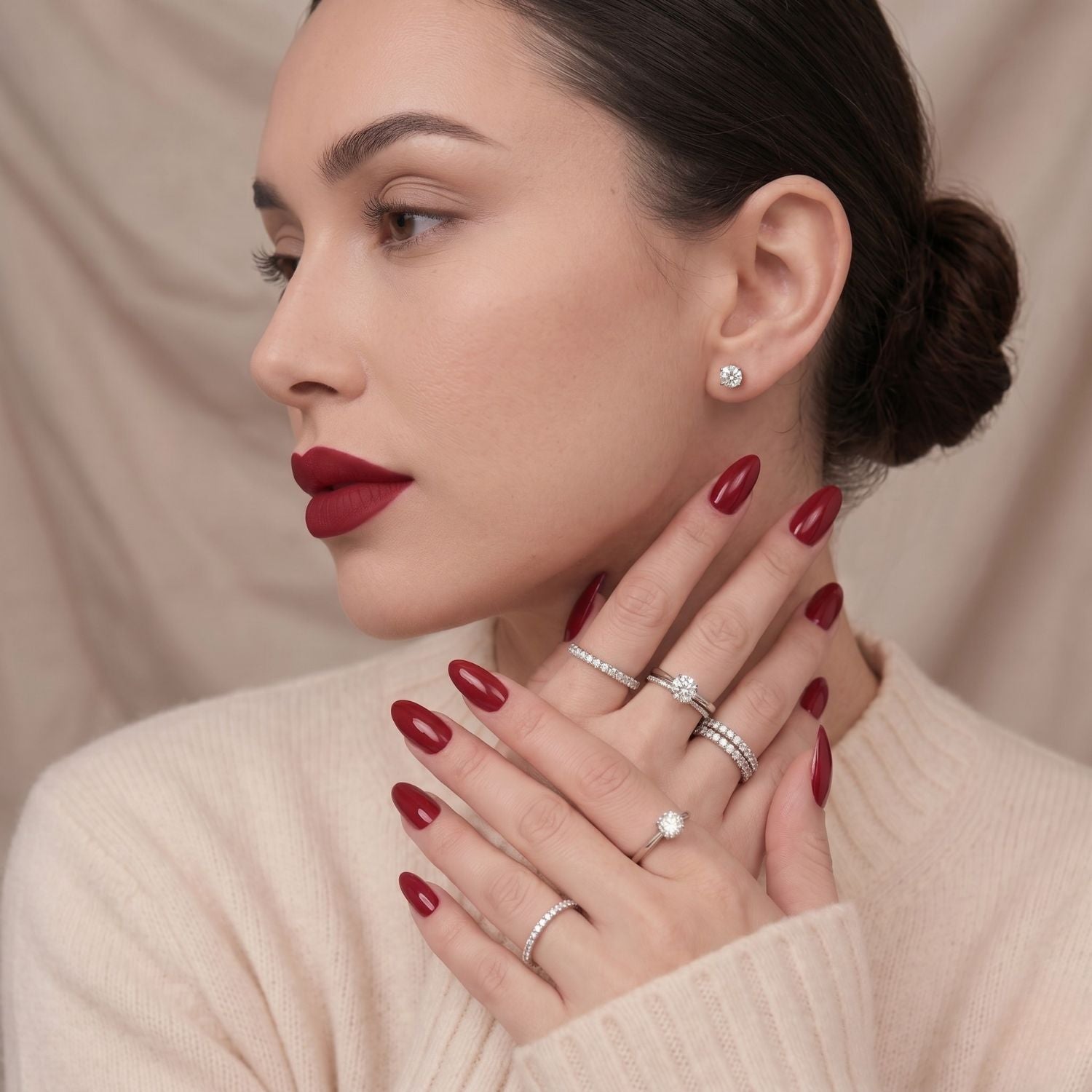 Ruby Romance wijnrode press-on nepnagels in amandelvorm. Elegante manicure op handen van model, bijpassende lippenstift
