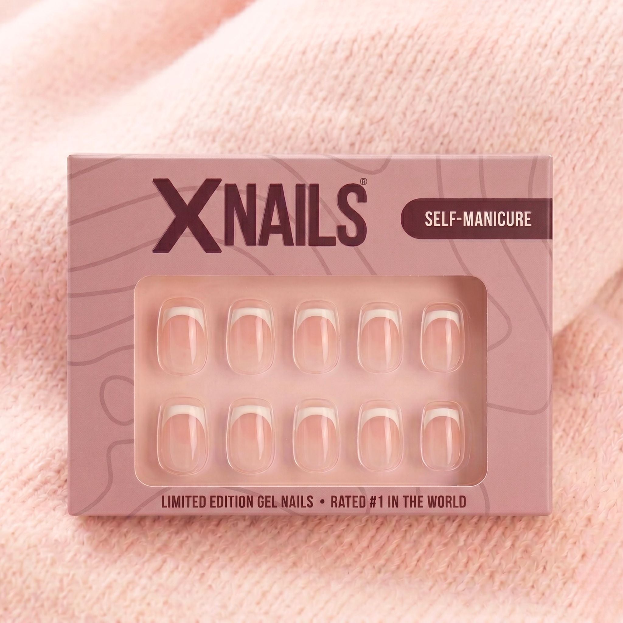 XNails-verpakking met witte Franse korte vierkante press-on nagels tegen roze gebreide achtergrond