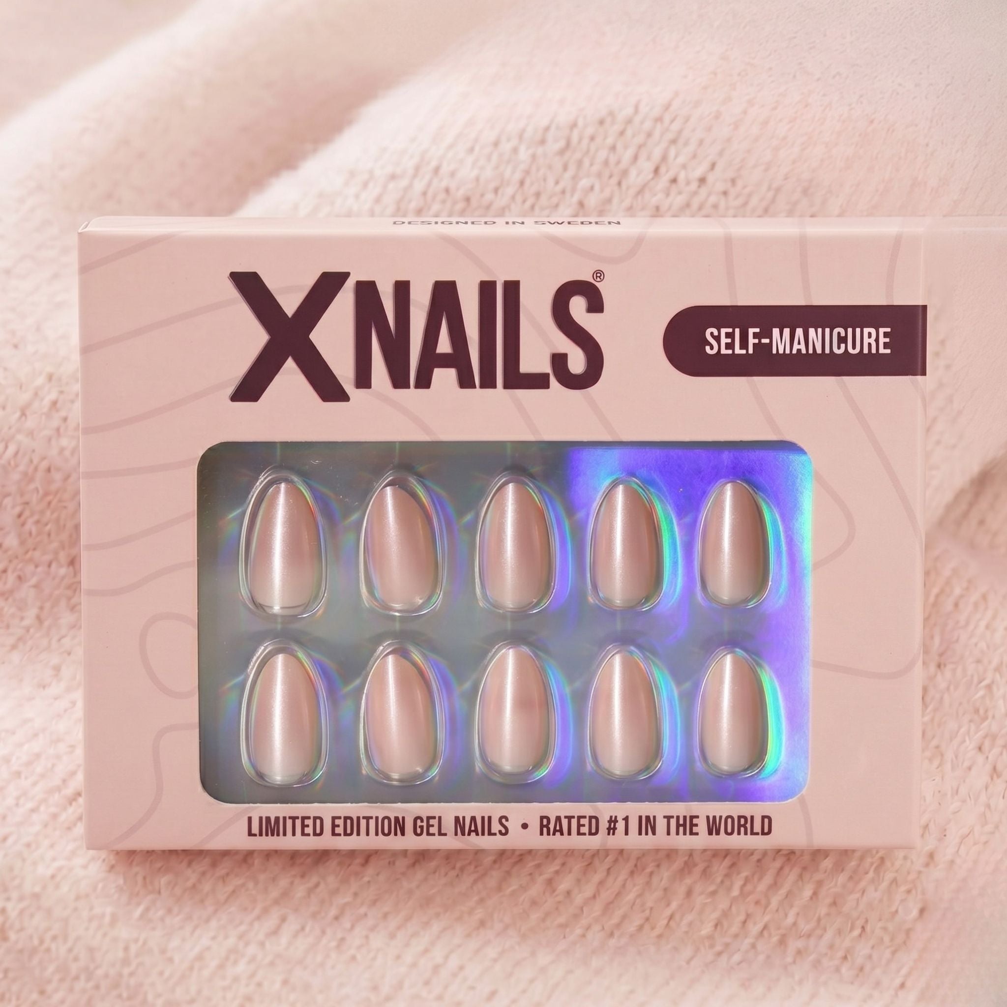 XNails-verpakking met zilveren chrome amandelvormige press-on nagels tegen roze gebreide achtergrond