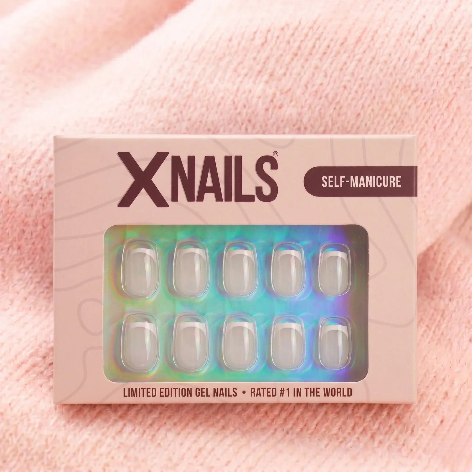 XNails-verpakking met french frost short square press-on nagels tegen een roze gebreide achtergrond