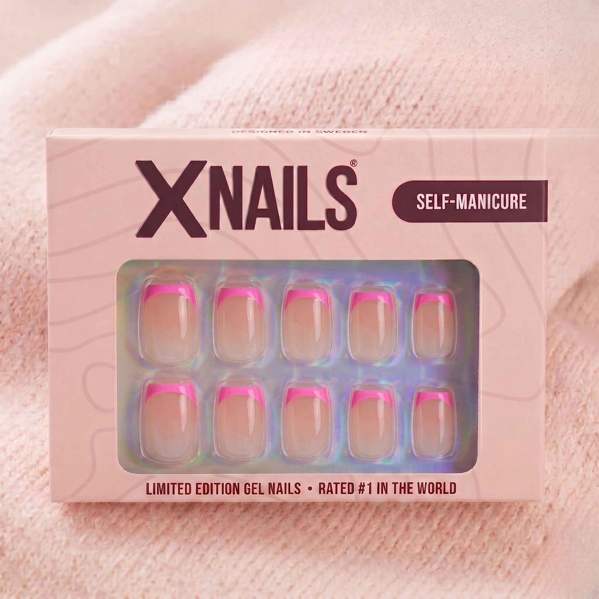 XNails-verpakking met roze Franse korte vierkante press-on nagels tegen roze gebreide achtergrond