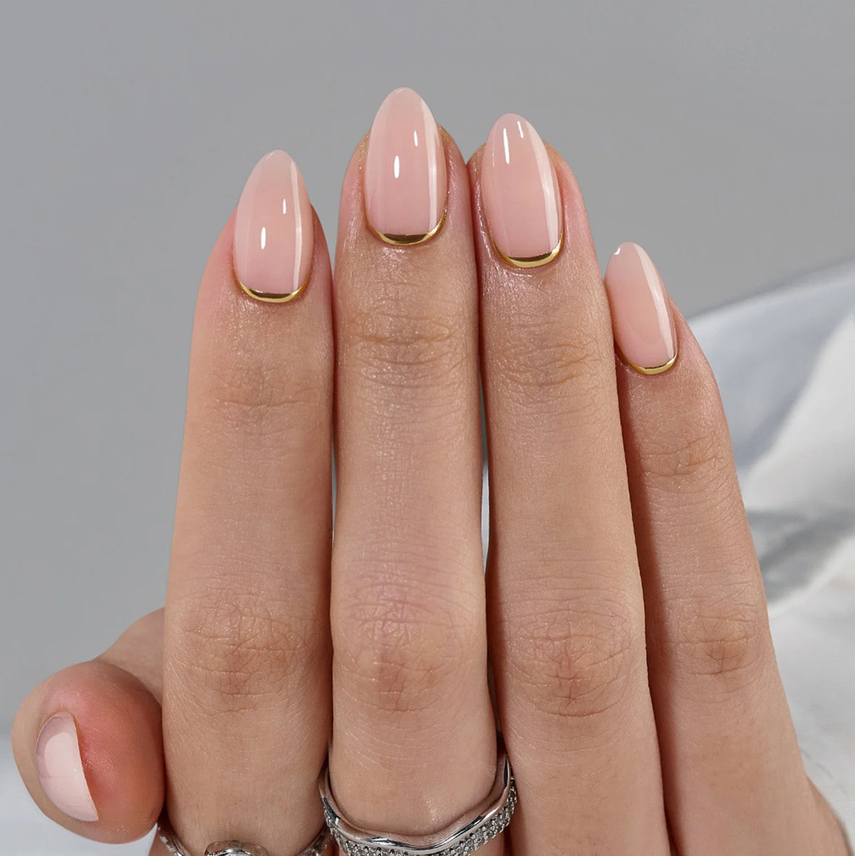 Golden Glimmer press-on nagels close-up – nude basis en gouden lijn langs de nagelriem