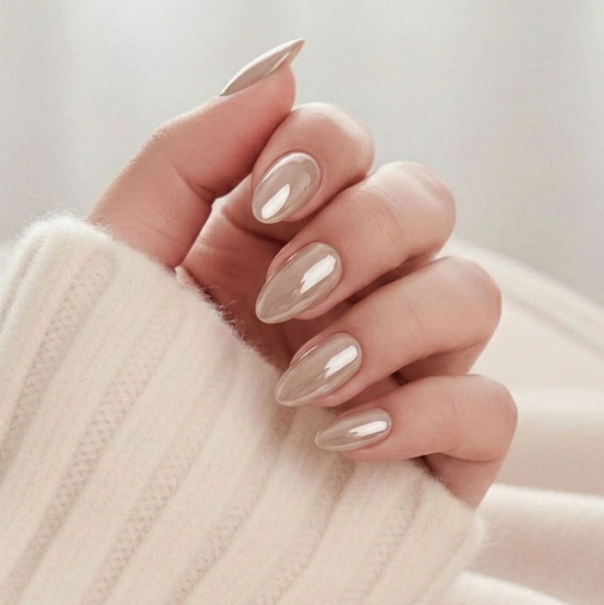 Pearly Perfection press-on nails – amandelvorm in pearl taupe met metallic glans tegen crèmewitte gebreide trui