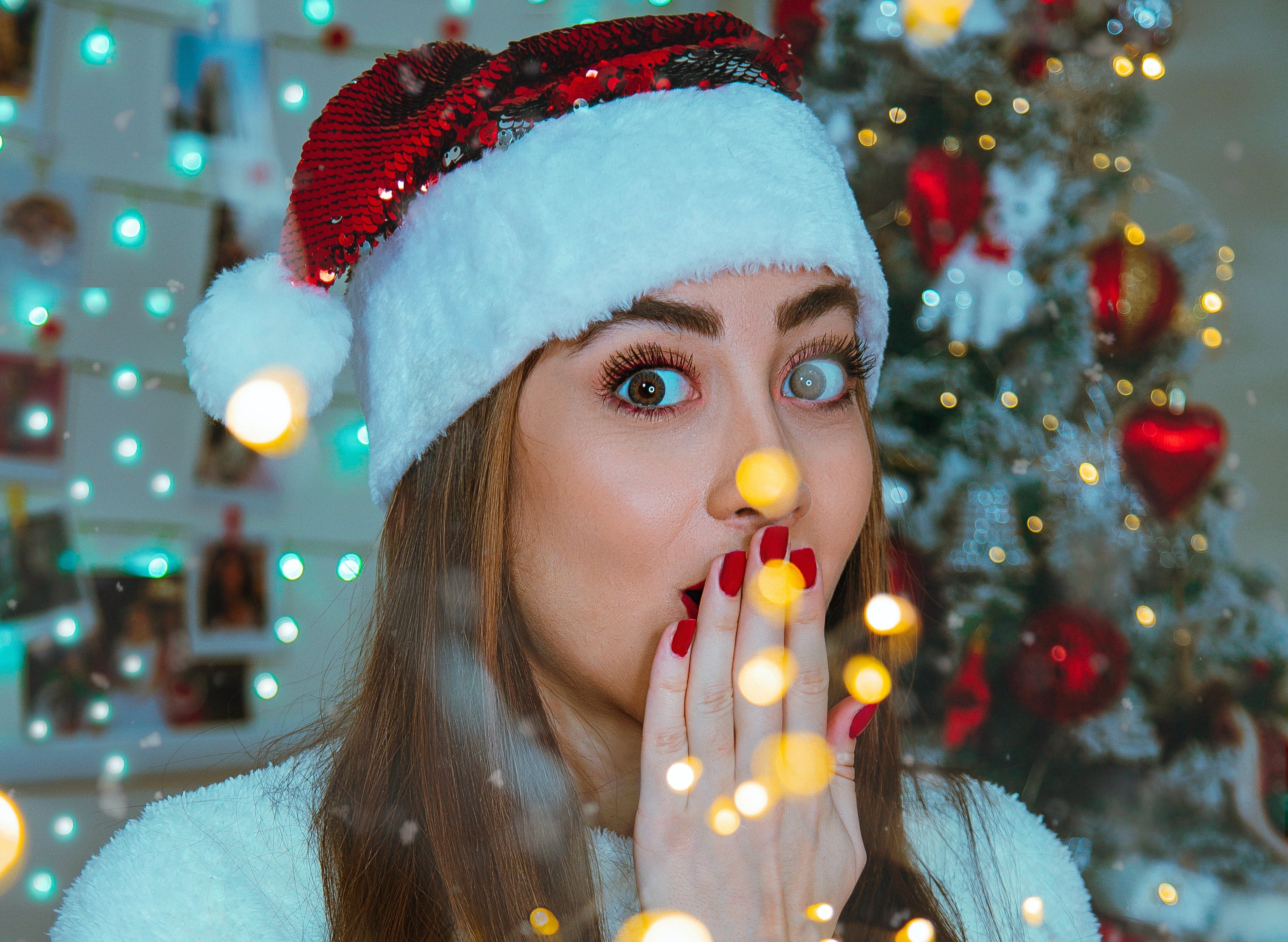 Vrouw met kerstmuts met rode press-on nagels voor een kerstboom en sterretjes