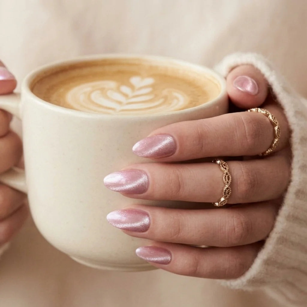 Powder Puff press-on nagels lifestyle – roze chrome amandelnagels houden een latte vast met gouden ringen